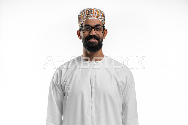 مفهوم تحسين الرؤية و محاولة تعديل البصر, إيماءات السعادة و السرور بوضوح الصورة, الرؤية من خلال العدسات الطبية, بورتريه مقرب لشاب عربي خليجي عماني يرتدي النظارة الخاصة بضعف النظر، صورة الجسم بالطول الكامل, خلفية بيضاء
