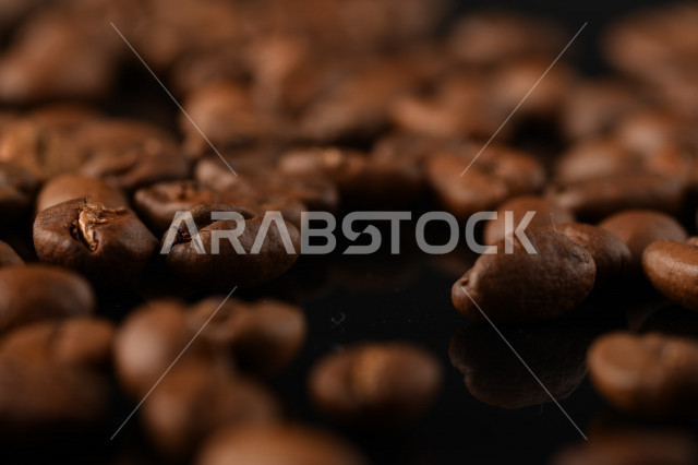 تناثر حبوب البن المحمصة على خلفية داكنة , حبوب بن القهوة البنية العضوية .