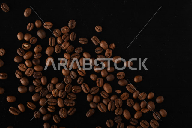 تناثر حبوب البن المحمصة على خلفية داكنة , حبوب بن القهوة البنية العضوية .
