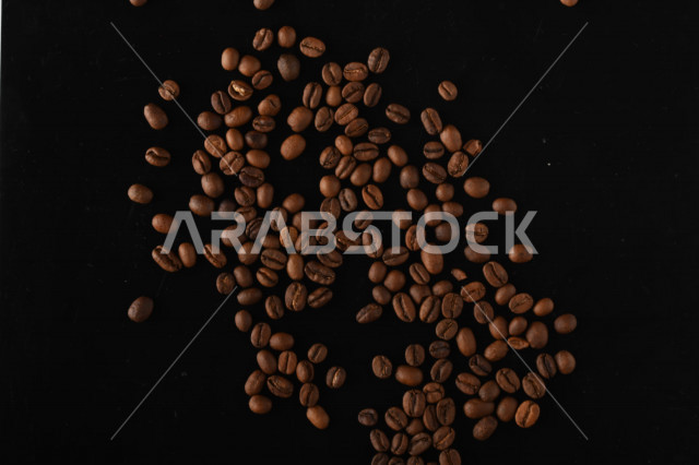 تناثر حبوب البن المحمصة على خلفية داكنة , حبوب بن القهوة البنية العضوية .
