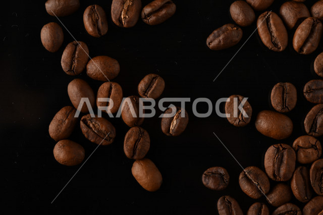 تناثر حبوب البن المحمصة على خلفية داكنة , حبوب بن القهوة البنية العضوية .
