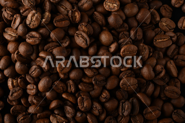 تناثر حبوب البن المحمصة على خلفية داكنة , حبوب بن القهوة البنية العضوية .