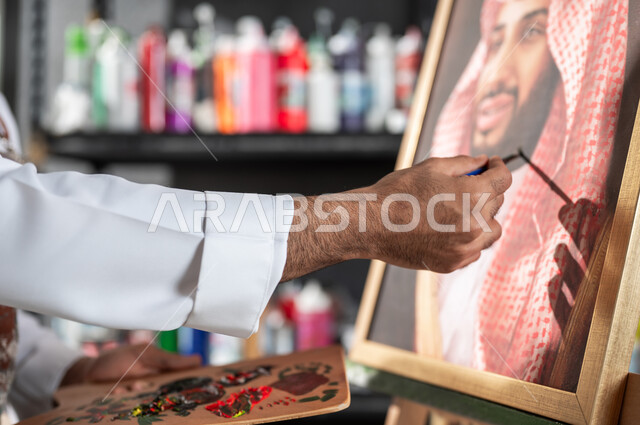 مفهوم الموهبة و الإبداع , الفخر و الاعتزاز بالانتماء للوطن العربي السعودي , ورشة عمل فنية , صورة مقربة ليد رسام عربي خليجي سعودي يقدم فنون الرسم و التلوين لصورة ولي العهد محمد بن سلمان