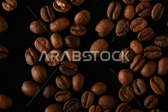 تناثر حبوب البن المحمصة على خلفية داكنة , حبوب بن القهوة البنية العضوية .