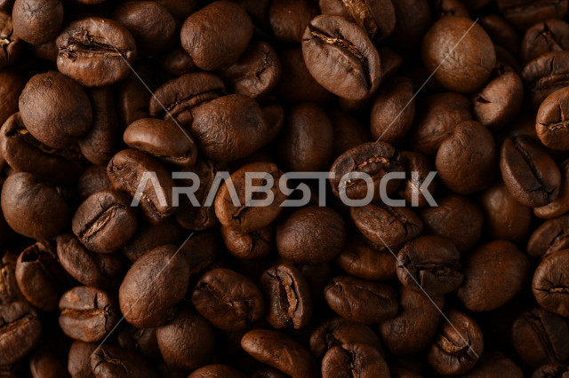 تناثر حبوب البن المحمصة على خلفية داكنة , حبوب بن القهوة البنية العضوية .