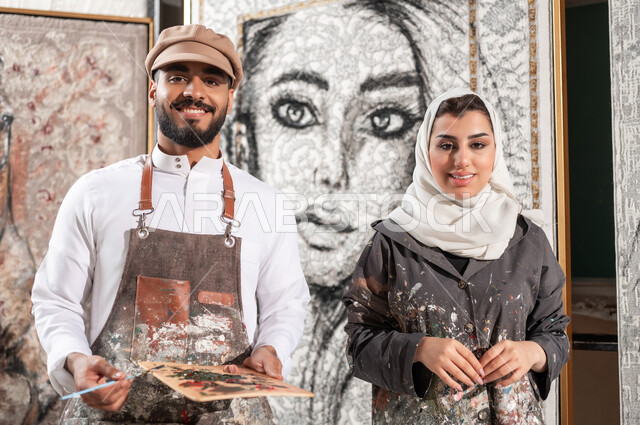استخدام أدوات و معدات الرسم , ممارسة الهوايات الفنية اليدوية , الاستمتاع بالأنشطة الترفيهية الممتعة , صورة مقربة لرسامان عربيان خليجيان سعوديان , النظر إلى الكاميرا بإيماءات الفرح و السرور