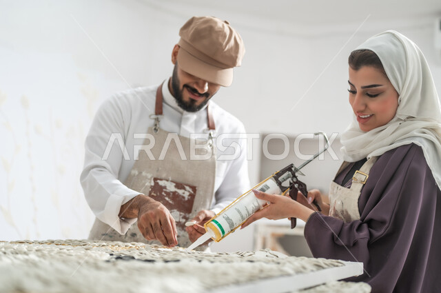 الفن الجداري ثلاثي الأبعاد , استخدام فرد السيليكون لتثبيت القطع البيضاء الصغيرة , رسامان عربيان خليجيان سعوديان يرتديان الثوب التقليدي و مريلة الرسم , التعاون على إنجاز مشروع فني ناجح , ورشة عمل فنية