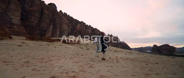 التشكيلات والتكوينات الصخرية في صحراء السعودية، إمتطاء الحصان على الرمال الناعمة في المناطق الصحراوية، توارث حب الخيول من الأجداد ونشره بين أبناء الوطن، ممارسة هواية ركوب الخيل وشغف الفروسية، رجل عربي خليجي سعودي يركب على ظهر جواد عربي أصيل