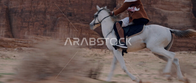 التشكيلات والتكوينات الصخرية في صحراء السعودية، إمتطاء الحصان على الرمال الناعمة في المناطق الصحراوية، توارث حب الخيول من الأجداد ونشره بين أبناء الوطن، شغف الفروسية وممارسة هواية ركوب الخيل، رجل عربي خليجي سعودي يركب على ظهر جواد عربي أصيل