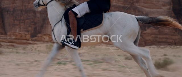 اتباع تقاليد الأجداد برعاية وتربية الجياد، التجول في الطبيعة الصحراوية على ظهر الحصان، علاقة أبناء الوطن بالخيل السعودي الأصيل، ممارسة هواية ركوب الخيل، صورة مقربة لرجل عربي خليجي سعودي يمتطي فرس، تشكيلات وتكوينات صخرية في صحراء السعودية
