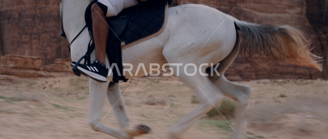 تكوينات وتشكيلات صخرية في صحراء السعودية، اتباع تقاليد الأجداد برعاية وتربية الجياد، التجول في الطبيعة الصحراوية على ظهر الحصان، علاقة أبناء الوطن بالخيل السعودي الأصيل، ممارسة هواية ركوب الخيل، صورة مقربة لرجل عربي خليجي سعودي يمتطي فرس