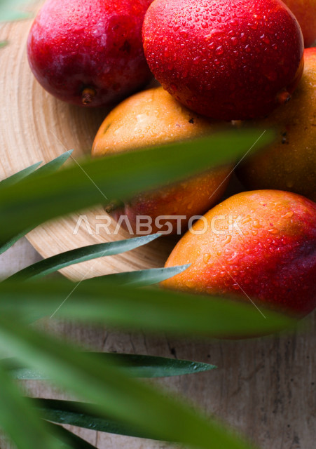 صورة مقربة لصحن من فاكهة المانجو الطازج على طاولة خشبية 