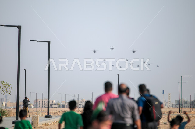 A group of citizens watching the Saudi National Day aviation team parade, showing loyalty and love for the Saudi state, commemorating the Saudi National Day on September 23, Flag Day activities on March 11, celebrating national holidays and events, presenting air shows in the skies of the Kingdom of Saudi Arabia.