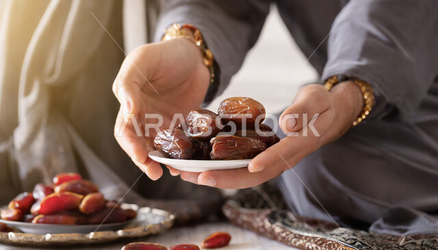 وجبة غذائية عالية الأهمية، غذاء صحي ومفيد، عادات وتقاليد المجتمع السعودي في الضيافة وحسن الاستقبال، محاصيل ومنتجات زراعية محلية وطنية سعودية، أنواع التمور الصحية الطازجة، ضيافة رمضانية لذيذة، صورة مقربة ليد إمرأة عربية خليجية سعودية تقوم بإكرام الضيوف