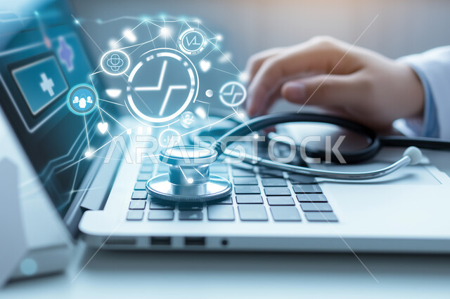 رموز رقمية هولوجرامية لأيقونات الكمبيوتر وشبكات الإنترنت، التطور الالكتروني والنمو التكنولوجي، صوة مقربة لأيدي طبيبة عربية خليجية سعودية تستخدم الحاسب المحمول مع سماعة طبية، التكنولوجيا الرقمية الحديثة