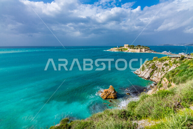 The view of clouds in the sky, rock formations and structures on the coast of the Red Sea, green wild plants on the plains of coastal areas in the city of Jeddah, famous landmarks and tourist places in the Kingdom of Saudi Arabia