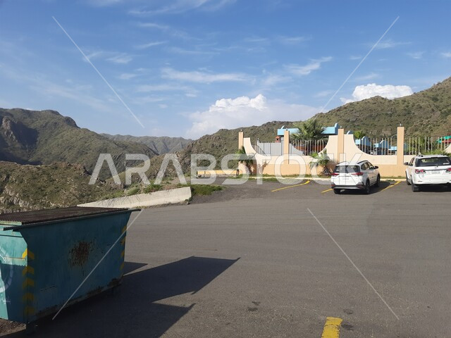 Paved asphalt roads and streets, parking in front of Barrahh Public Park in Al Bahah City, recreational family parks and gardens in the Kingdom of Saudi Arabia, interest in natural areas and green trees.