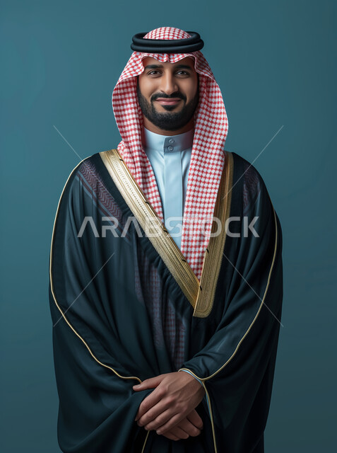 الأناقة والاهتمام بالمظهر الخارجي, بورتريه لشاب عربي خليجي سعودي أنيق يرتدي الزي التقليدي والبشت ينظر إلى الكاميرا بإيماءات السعادة والفرح, الابتسام والتفاؤل وحب الحياة, خلفية زرقاء