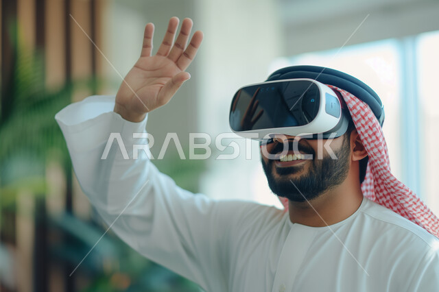 الإندماج والتفاعل ومحاكاة العالم الخيالي, صورة مقربة لرجل عربي سعودي خليجي يرتدي نظارة الواقع الإفتراضي يرفع يده للاعلى بإيماءات التلويح، مفهوم التسليه والترفيه, قضاء وقت ممتع, تطور التقنيه والتكنولوجيا