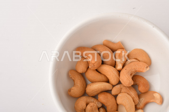 الكاجو(الكاشو) نوع من انواع المكسرات المشهورة , الكاجو المملح , مكسرات صحية ولذيذة , عنصر غذائي مفيد للصحة , وجبة خفيفة , خلفية بيضاء