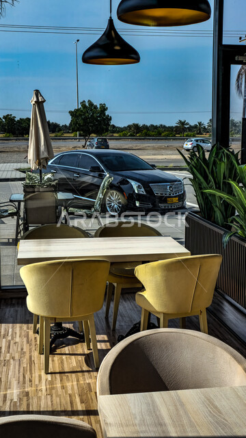 مفهوم التنزه في أوقات الفراغ في العطلة الصيفية, الكراسي و الطاولات في إحدى المطاعم في منطقة السوادي, قضاء أوقات ممتعه في الكافيهات ,سيارة تقف في شوارع و طرقات سلطنة عمان, الاهتمام في زراعة الاشجار الخضراء