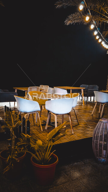 Chairs and tables in one of the luxurious restaurants in the Sultanate of Oman, enjoying the quiet atmosphere at night, interest in planting green plants, the concept of hiking and entertainment in the summer atmosphere