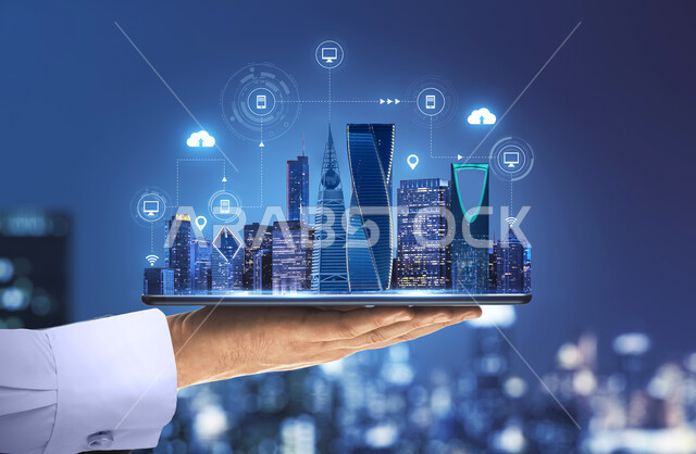 التقدم العمراني في المملكة العربية السعودية, النمو والتطور الرقمي, رجل عربي خليجي سعودي يحمل بيده مجسم لأبراج مدينة الرياض, البناء التكنولوجي المعماري المستقبلي, رؤية مستقبلية سعودية 2030