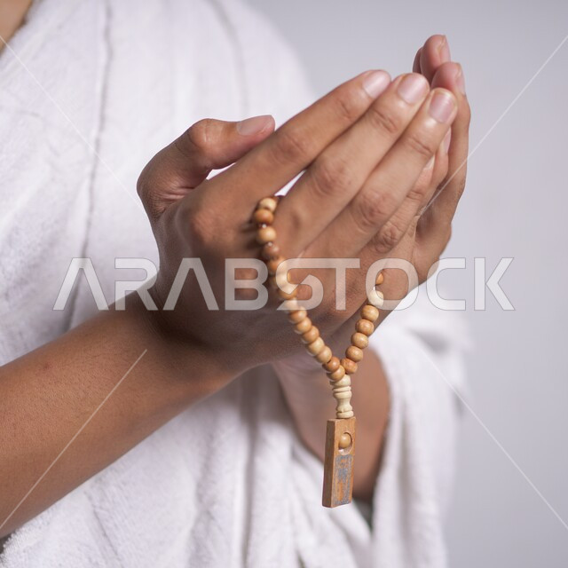أداء الفرائض والعبادات والتقرب إلى الله, رجل مسلم يلبس ثياب الإحرام ويرفع يديه للدعاء والتضرع,الإمساك بالسبحة وكثرة الاستغفار, توجه المسلمين لأداء مناسك الحج والعمرة