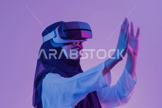 أجهزة تكنولوجية وتقنيات حديثة، رفع الايدي عاليا بتعابير محاولة لمس شيء ما, دمج العالم الخيالي مع المتعة والتسلية، بورتريه لامرأة عربية خليجية سعودية ترتدي نظارة الواقع الإفتراضي تقوم باللعب في ألعاب الفيديو الترفيهية، قضاء وقت ممتع في اللعب, خلفية ملونة