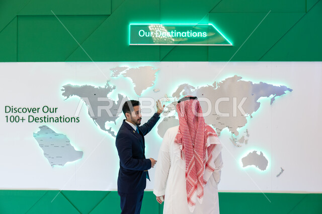 النقل الجوي المستدام وتعزيز الابتكار والتبادل الثقافي، الوقوف امام شاشة الكترونيه ثلاثية الابعاد لخريطة العالم، رؤية مستقبلية سعودية 2030، حوارات ومناقشات عالميه، رجل عربي سعودي خليجي مع رجل يرتدي البدله الرسميه في مؤتمر مستقبل الطيران في مدينة الرياض