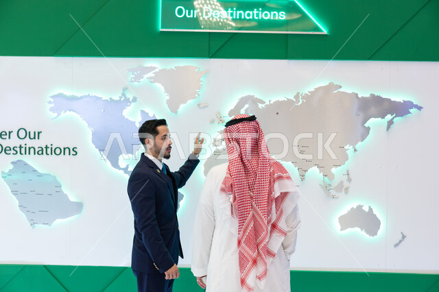 تعزيز الابتكار والنقل الجوي المستدام والتبادل الثقافي، الوقوف امام شاشة الكترونيه ثلاثية الابعاد لخريطة العالم، رؤية مستقبلية سعودية 2030، حوارات ومناقشات عالميه، رجل عربي سعودي خليجي مع رجل يرتدي البدله الرسميه في مؤتمر مستقبل الطيران في مدينة الرياض