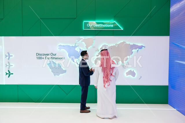 توسيع سبل التعاون في قطاع الطيران المدني، الوقوف امام شاشة الكترونيه ثلاثية الابعاد لخريطة العالم، رؤية مستقبلية سعودية 2030، حوارات ومناقشات عالميه، رجل عربي سعودي خليجي مع رجل يرتدي البدله الرسميه في مؤتمر مستقبل الطيران في مدينة الرياض