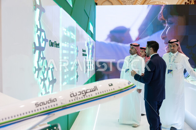 رؤية مستقبلية سعودية 2030، حوارات ومناقشات عالميه، رجال عرب سعوديين خليجيين مع رجل يرتدي البدله الرسميه في مؤتمر مستقبل الطيران في مدينة الرياض، الوقوف امام شاشة الكترونيه ثلاثية الابعاد لخريطة العالم، توسيع سبل التعاون في قطاع الطيران المدني