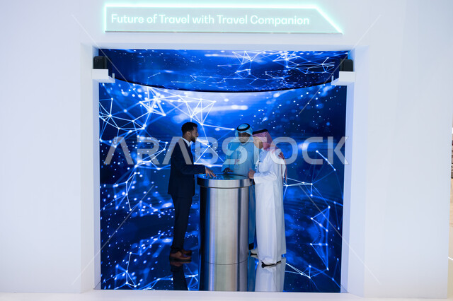 توسيع سبل التعاون في قطاع الطيران المدني، شاشة الكترونيه ثلاثية الابعاد لمخططات هولوجرامية، رؤية مستقبلية سعودية 2030، حوارات ومناقشات عالميه، رجلان عربيان سعوديان خليجيان مع رجل يرتدي البدله الرسميه يقفان في مؤتمر مستقبل الطيران في مدينة الرياض