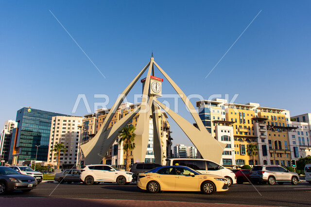 النمو والتقدم العمراني في الإمارات العربية المتحدة، معالم وأماكن سياحية مشهورة، حركة المرور للسيارات في الطرقات والشوارع الاسفلتية، الفن الهندسي المعماري على الطراز الحديث لبرج الساعة في ديرة في مدينة دبي وقت النهار، المباني والمنشآت السكنية والتجارية