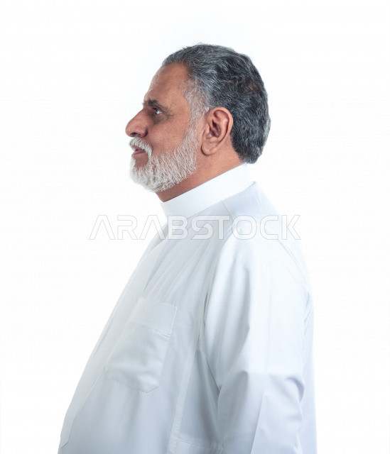 Portrait of an old Saudi Arab man doing photo sessions, wearing a white dress, white background, side view of an elderly man taking pictures, concept of facial expression and body language