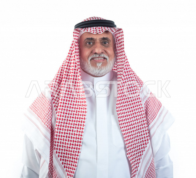 بورتريه رجل عربي سعودي كبير بالسن مبتسم يقوم بجلسات التصوير , صورة مقربة , شايب سعودي يرتدي ثوب أبيض مع شماغ وعقال , خلفية بيضاء , رجل مسن بشوش الوجه يلتقط الصور , مفهوم تعابيرالوجه 