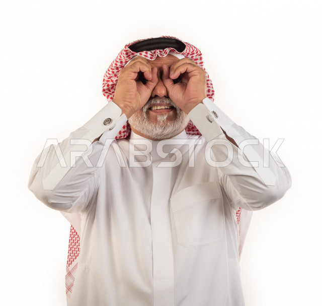 بورتريه رجل عربي سعودي كبير بالسن بإيماءات وجه ويدين مختلفة , صورة مقربة , شايب سعودي يرتدي ثوب أبيض مع شماغ وعقال , خلفية بيضاء , رجل مسن يلتقط الصور بتعابيرالوجه ولغة الجسد المختلفة