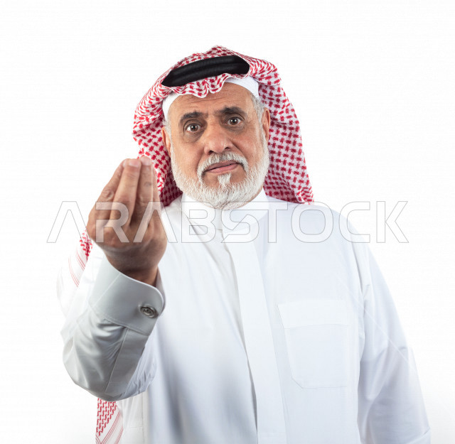 بورتريه رجل عربي سعودي كبير بالسن بإيماءات وجه ويدين مختلفة , صورة مقربة , شايب سعودي يرتدي ثوب أبيض مع شماغ وعقال , خلفية بيضاء , رجل مسن يشير بيده على الإنتظار والصبر , مفهوم تعابيرالوجه ولغة الجسد