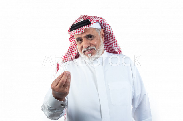بورتريه رجل عربي سعودي كبير بالسن بإيماءات وجه ويدين مختلفة , صورة مقربة , شايب سعودي يرتدي ثوب أبيض مع شماغ وعقال , خلفية بيضاء , رجل مسن يشير بيده على الإنتظار والصبر , مفهوم تعابيرالوجه ولغة الجسد