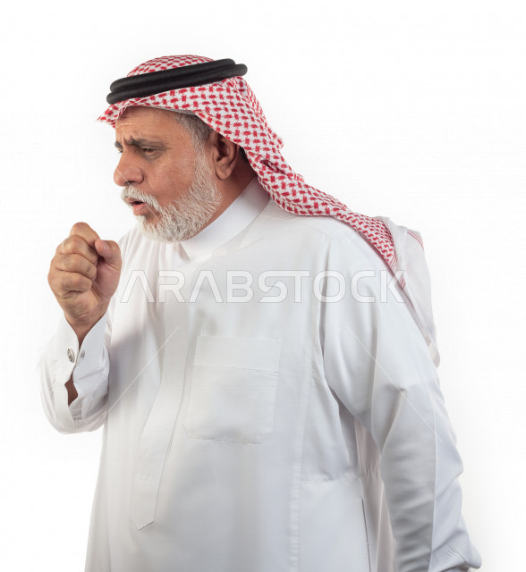 بورتريه رجل عربي سعودي كبير بالسن يضع يده أمام فمه وهو يسعل بإيماءات وجه ويدين مختلفة , صورة مقربة , شايب سعودي يرتدي ثوب أبيض مع شماغ وعقال , خلفية بيضاء , منظر جانبي لرجل مسن يسعل ويكح , مفهوم تعابيرالوجه ولغة الجسد المختلفة