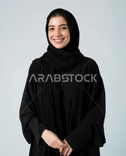 الملابس العصرية للمحجبات، الوقوف باستقامة والنظر الى الكاميرا، صور شخصية للوثائق الرسمية، الأناقة والإهتمام بالمظهر الخارجي، مفهوم النعومة والأنوثة، بورتريه مقرب لامرأة عربية خليجية سعودية محجبة ترتدي عباءة سوداء تنظر بايماءات السعادة والسرور، خلفية بيضاء