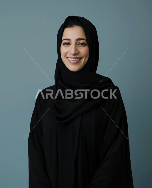 الأزياء العصرية للمحجبات، الأناقة والإهتمام بالمظهر الخارجي، مفهوم النعومة والأنوثة، ايماءات السعادة والسرور، الصور الشخصية للوثائق الرسمية، بورتريه مقرب لامرأة عربية خليجية سعودية محجبة ترتدي عباءة سوداء تنظر الى الكاميرا وتقف باستقامة، خلفية رمادية