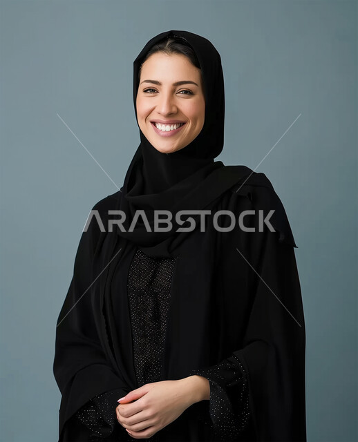 The concept of softness and femininity, interest in appearance and elegance, gestures of happiness and pleasure, personal photos for official documents, modern fashion for veiled women, close-up portrait of a veiled Saudi Arabian Gulf woman wearing a black abaya looking at the camera and standing straight, gray background