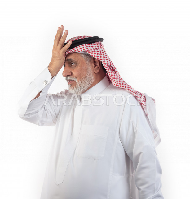 بورتريه رجل عربي سعودي كبير بالسن يضع يده على رأسه بإيماءات وجه ويدين مختلفة , صورة مقربة , شايب سعودي يرتدي ثوب أبيض مع شماغ وعقال , خلفية بيضاء , منظر جانبي لرجل مسن يضع يده على مقدمة رأسه في حالة من الصدمة والهم والحزن , مفهوم تعابيرالوجه ولغة الجسد ال