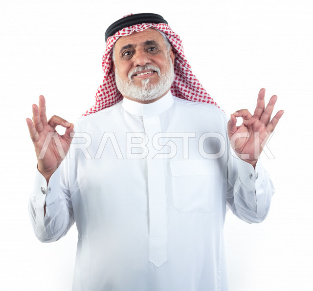 بورتريه رجل عربي سعودي كبير بالسن بإيماءات وجه ويدين مختلفة , صورة مقربة , شايب سعودي يرتدي ثوب أبيض مع شماغ وعقال , خلفية بيضاء , مفهوم تعابيرالوجه ولغة الجسد