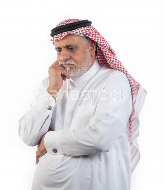 Portrait of an old Saudi Arab man putting his hand on his cheek in a state of sadness and unhappiness, wearing a white dress with a shemagh and headband, white background, an elderly man in a state of deep thought, the concept of body language and facial 
