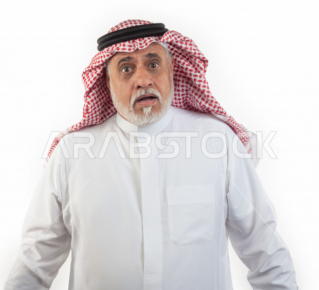 بورتريه رجل عربي سعودي كبير بالسن ينظر في حالة من الذهول والاستغراب , يرتدي ثوب أبيض مع شماغ وعقال , خلفية بيضاء , رجل مسن ينظر بصدمة ودهشة , مفهوم لغة الجسد وتعابيرالوجه