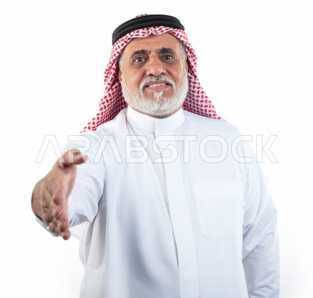 بورتريه رجل عربي سعودي كبير بالسن يمد يده للمصافحة , يرتدي ثوب أبيض مع شماغ وعقال , خلفية بيضاء , رجل مسن يمد يده للمصافحة وإلقاء التحية والسلام مفهوم تعابير الوجه ولغة الجسد المختلفة