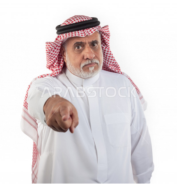 بورتريه رجل عربي سعودي كبير بالسن يشير بإصبعه بحالة من الغضب , يرتدي ثوب أبيض مع شماغ وعقال , خلفية بيضاء , رجل مسن غاضب يشير بإصبعه مفهوم تعبير الوجه
